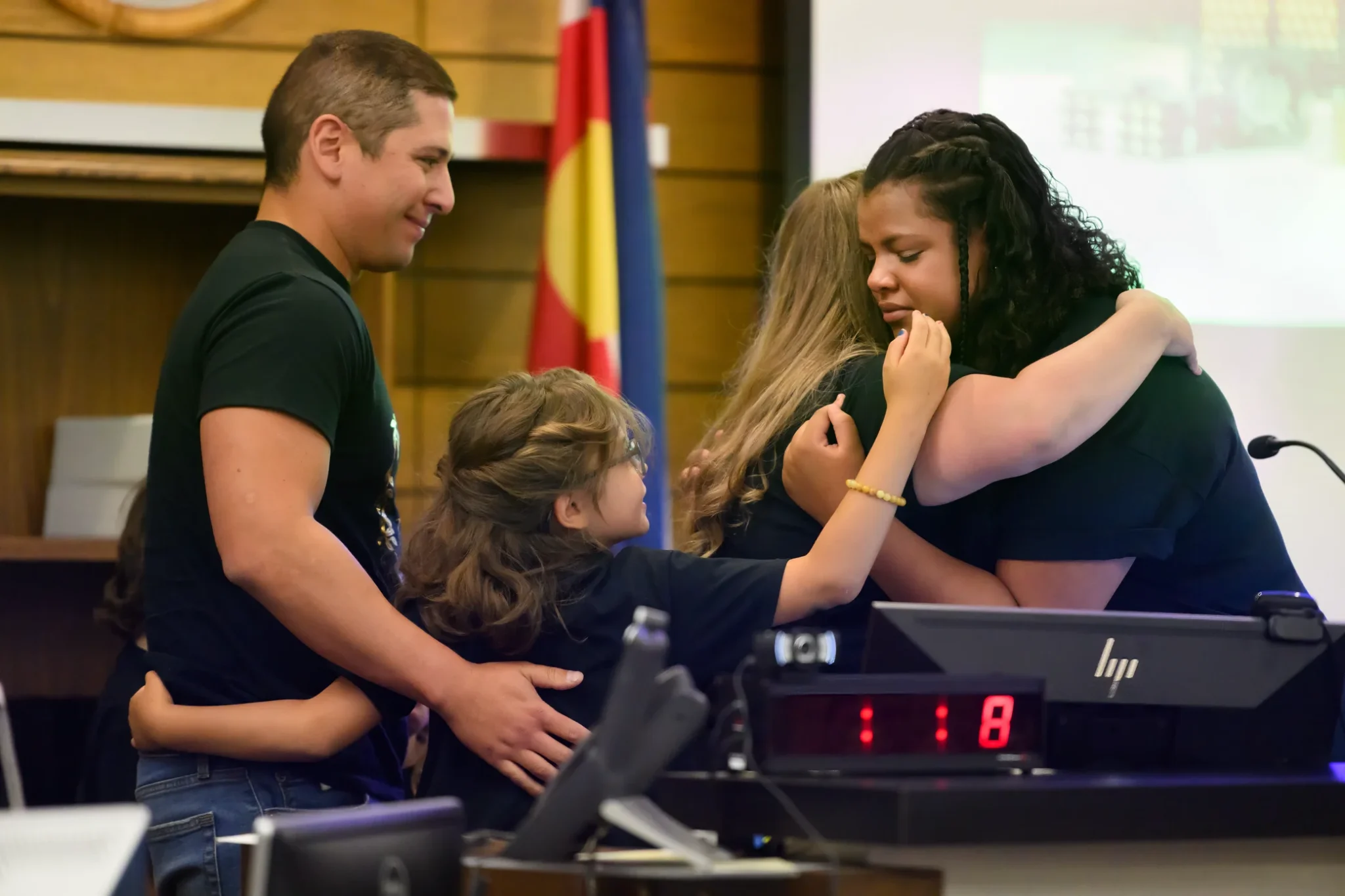 A foster family shares an emotional hug, symbolizing the support and care fostered within their community.