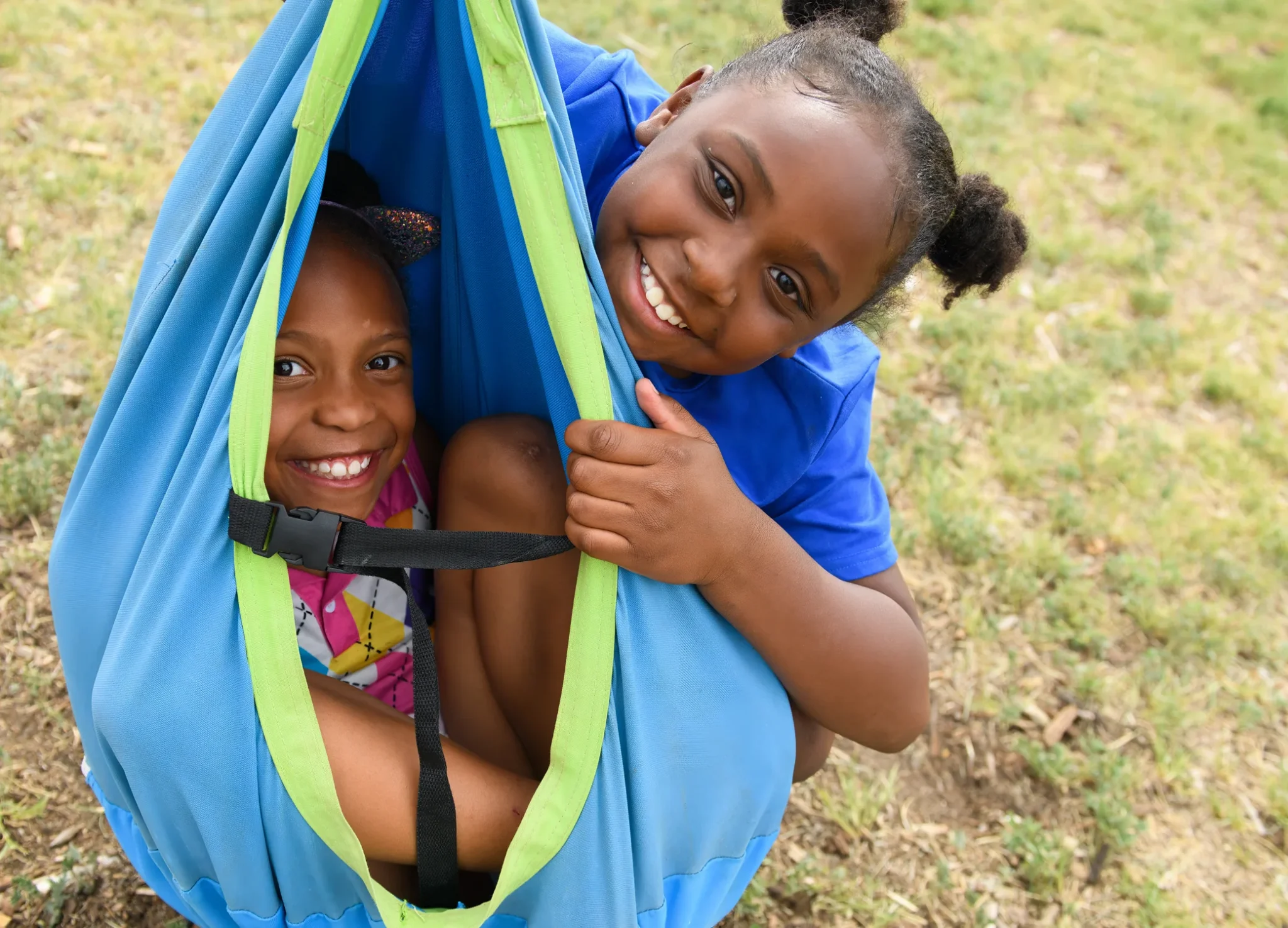 Two smiling children enjoying a swing outdoors, symbolizing joy and support in foster families.