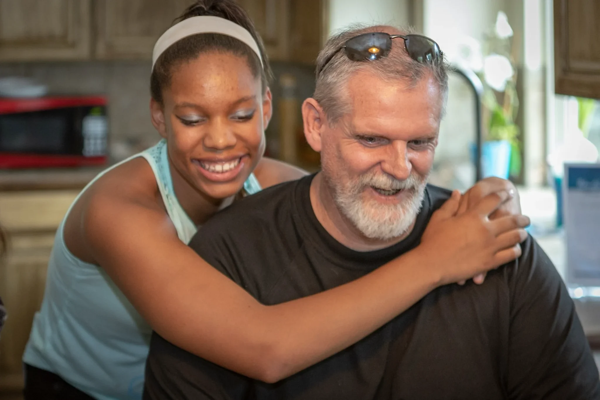 Foster family support with a smiling child embracing an adult.