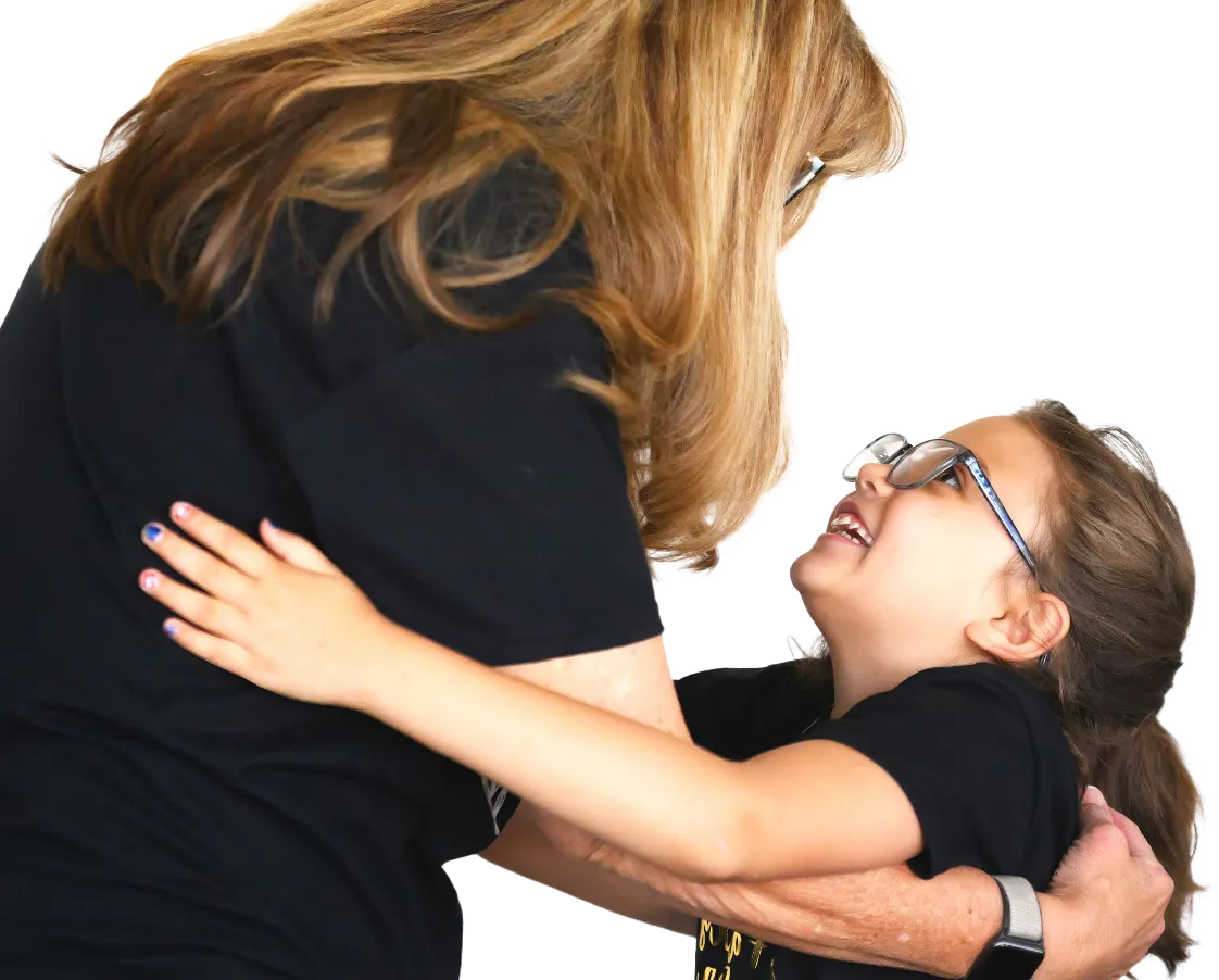 Woman giving a warm hug to a smiling child, symbolizing support in foster families.