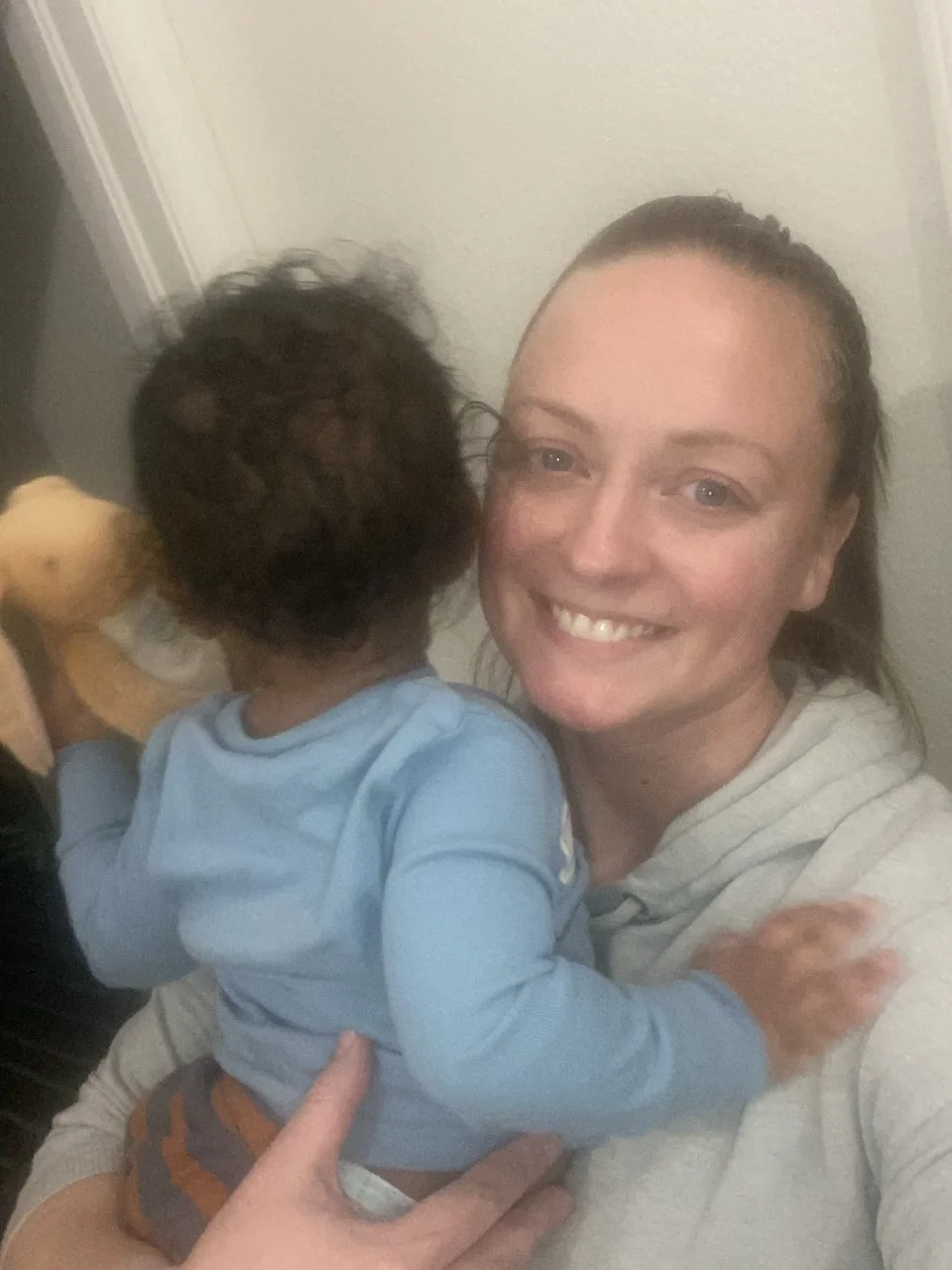 Smiling foster parent holding a young child, highlighting love and support within foster families.
